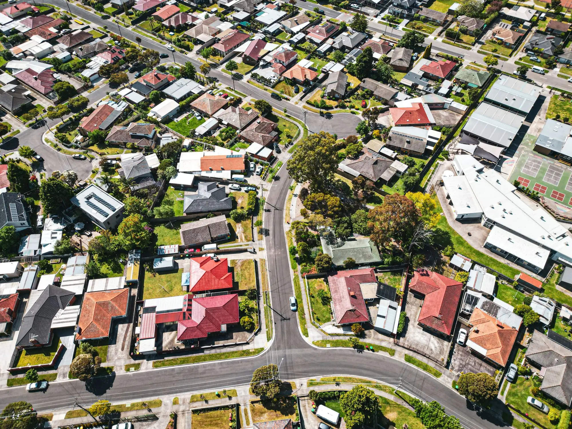 Aerial view of tiled and metal roofs across a Melbourne suburb, the kind of streets roofers work through in storm season